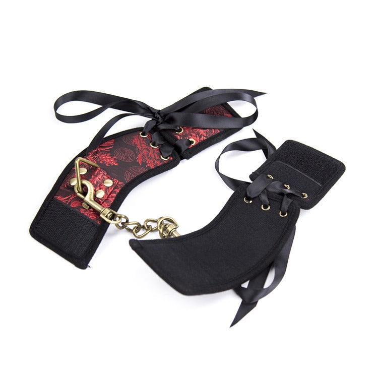 Velcro hand cuffs with red ribbon and gold accents for restraint play